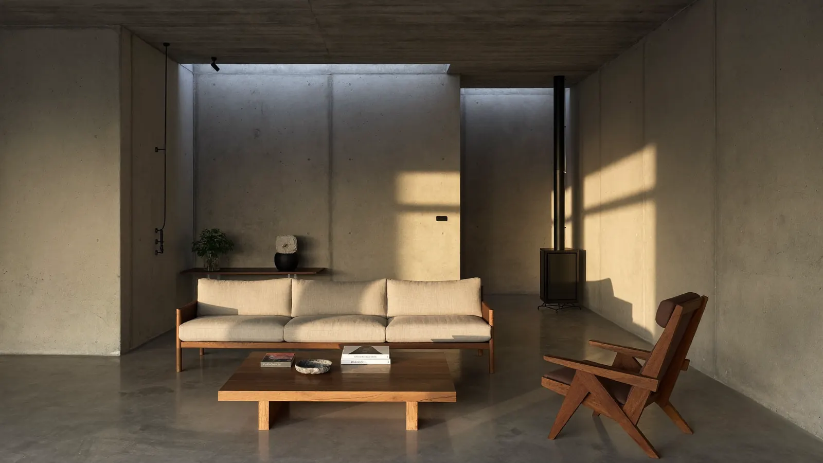 Living de hormigón con sofá de nogal y lino, mesa ratona de roble y sillón de madera